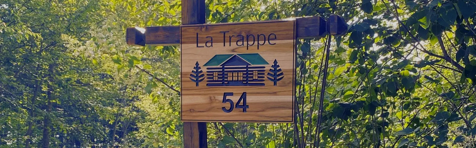 Pancarte extérieure en bois installée sur poteau à l’entrée d’un chalet en milieu boisé