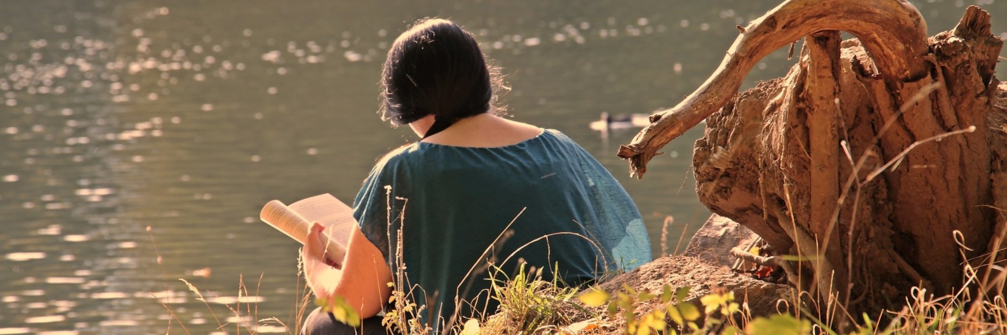femme lisant sur le bord d'un lac